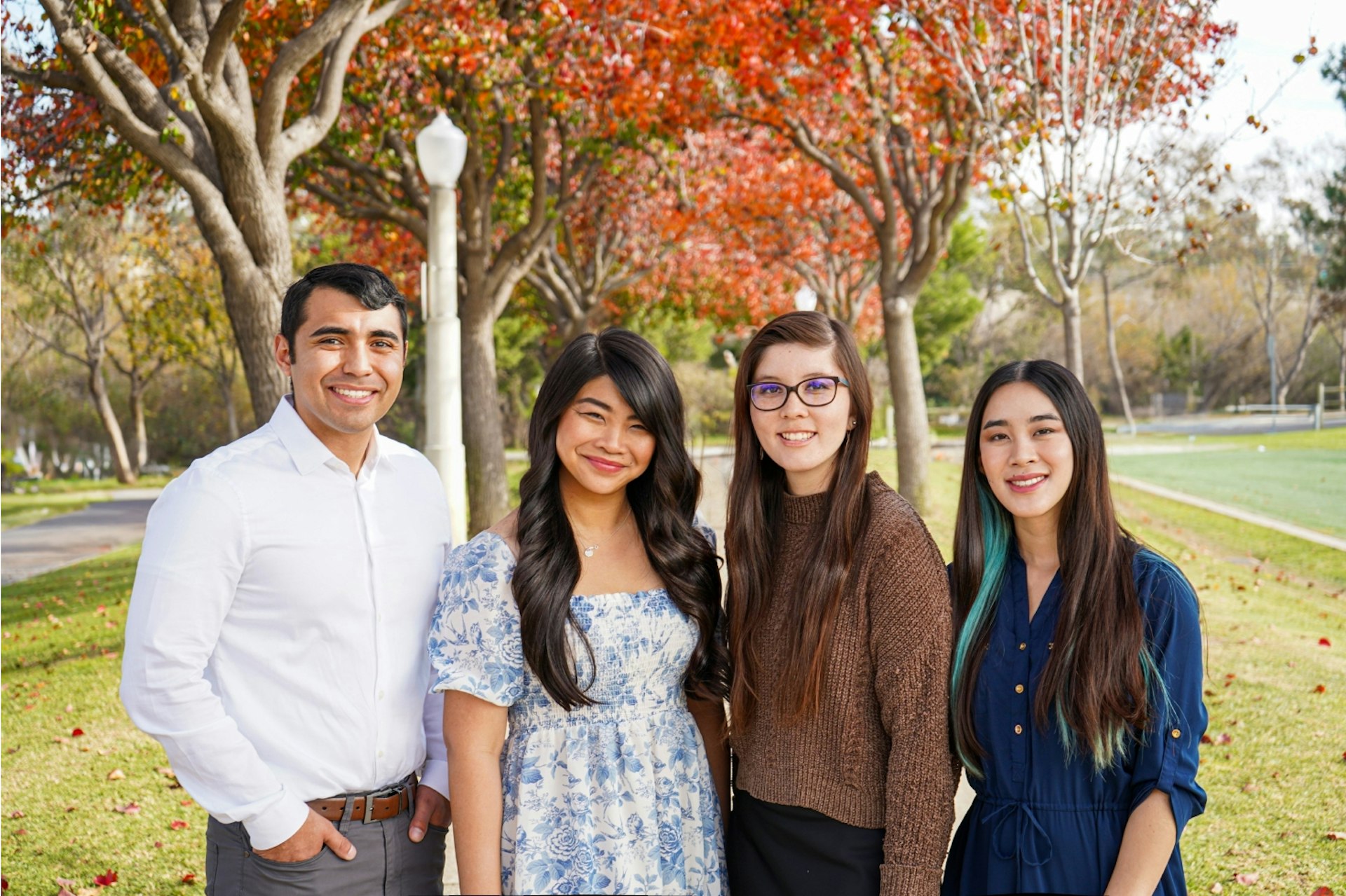 Three female and one male teacher standing together in a park