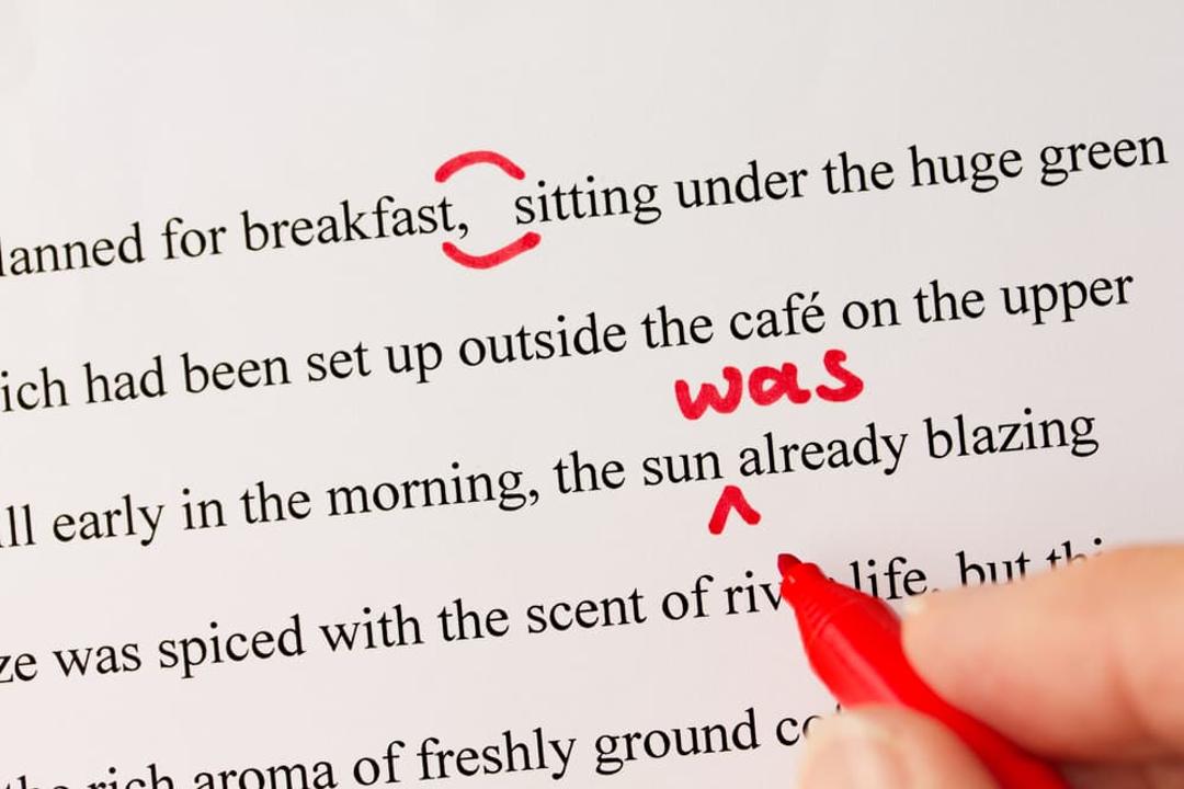 Proofreading paragraph with a red pen.