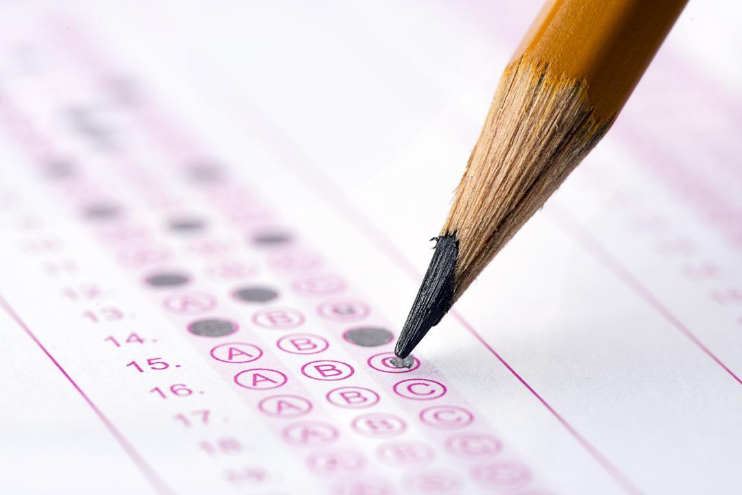 A pencil and a multiple-choice exam form with answers marked.