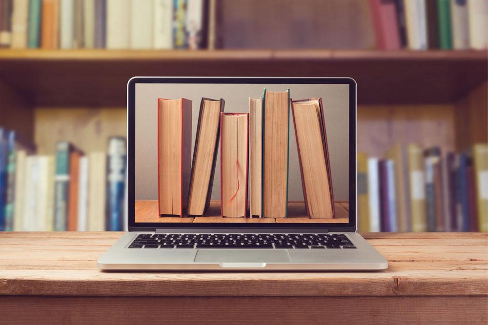 A laptop with an image of a pile of books displayed on its screen.